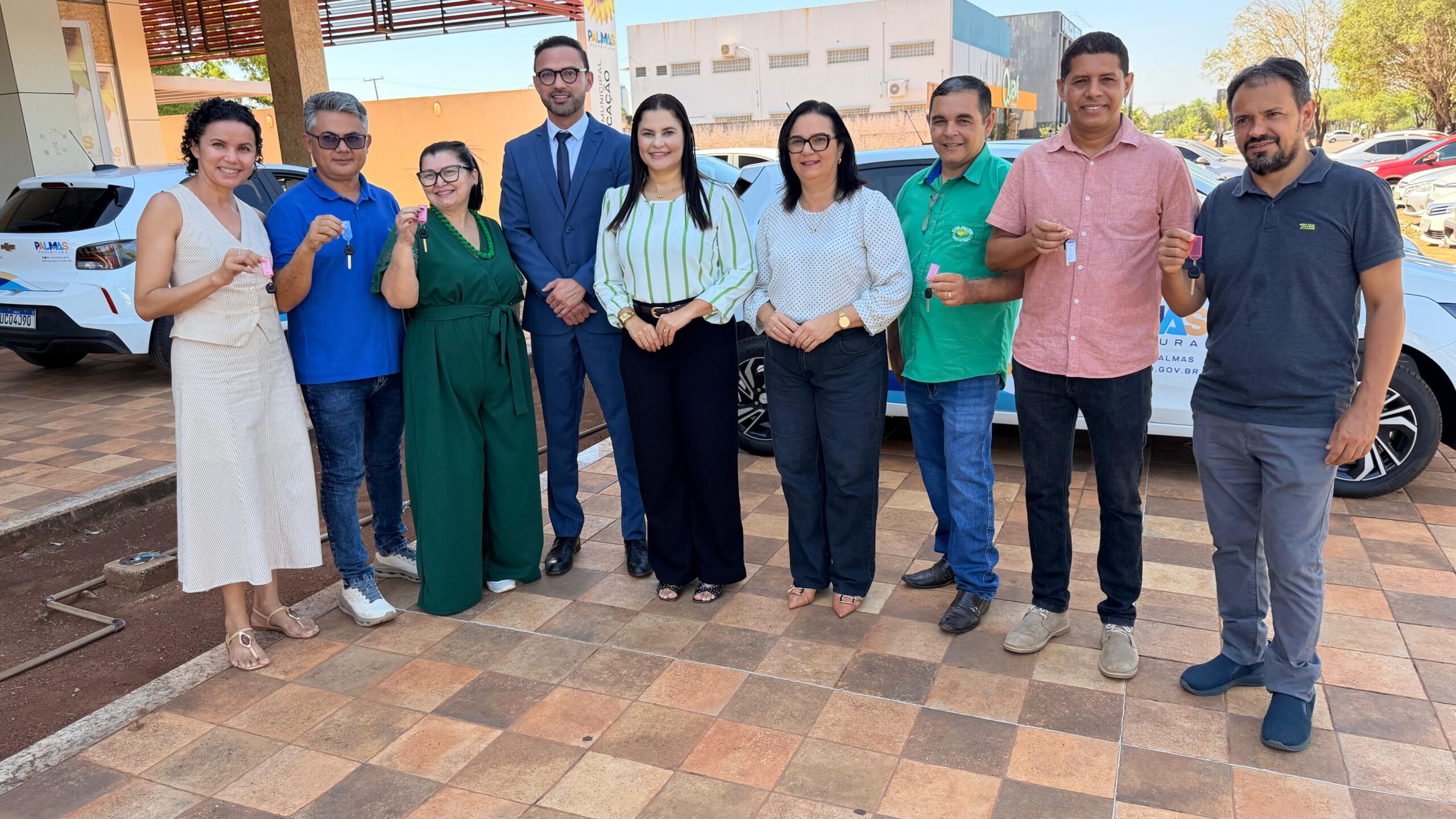 Gestores exibem chaves diante de carros brancos identificados com a Prefeitura de Palmas.