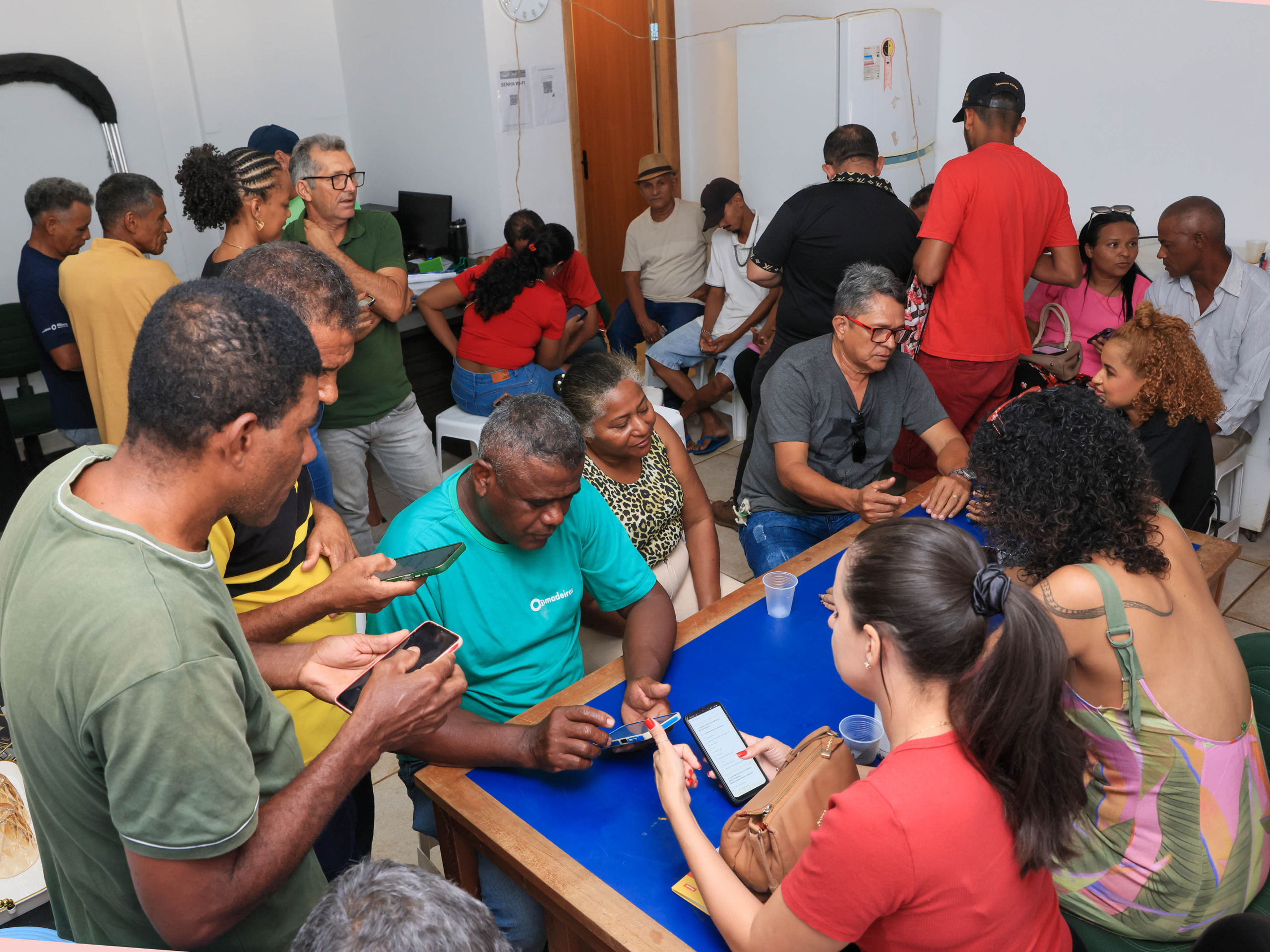 Adultos reunidos em sala ao redor de mesa azul durante atividade relacionada ao mapeamento em Palmas.